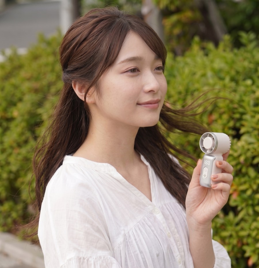 携帯扇風機を使う女性