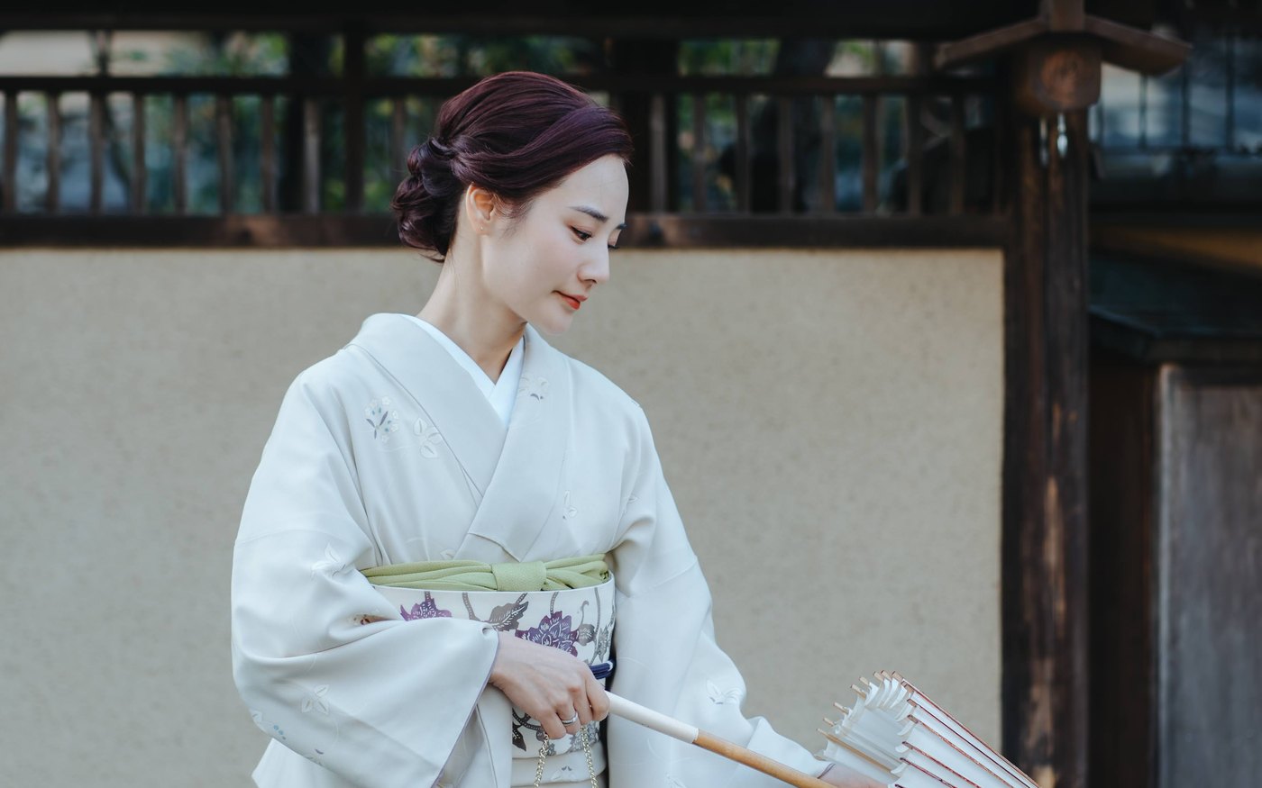 和傘を広げる白い正絹の着物姿の女性