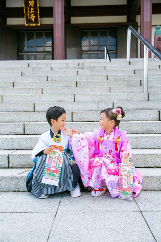 千歳飴を持って階段に腰かける羽織袴の男の子と被布姿の女の子