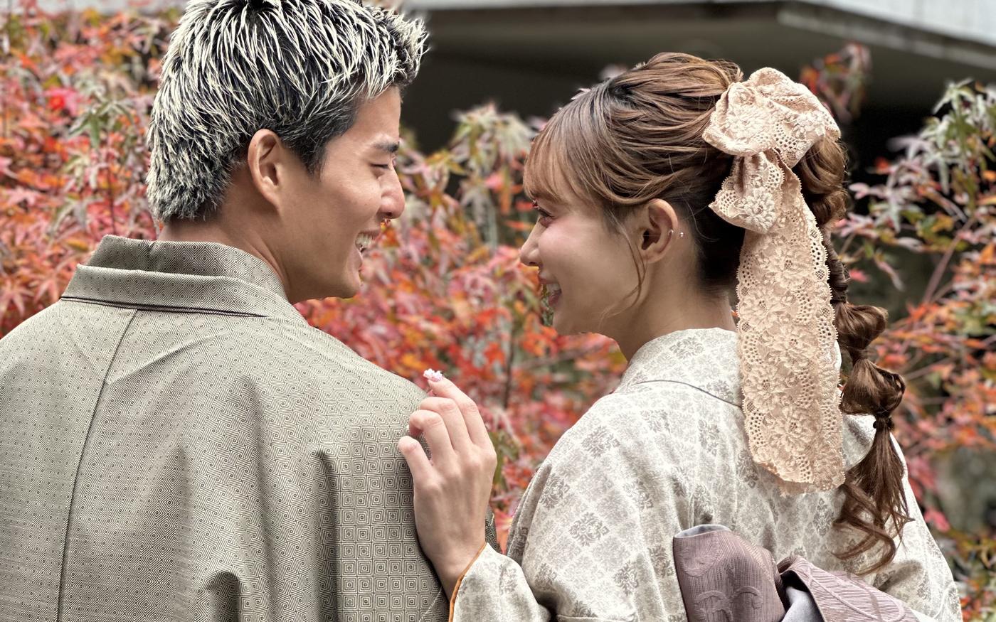 紅葉を背に向かい合うカジュアル着物姿のカップル