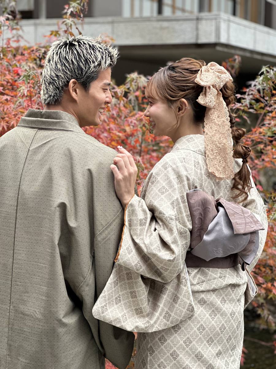 紅葉を背に向かい合うカジュアル着物姿のカップル