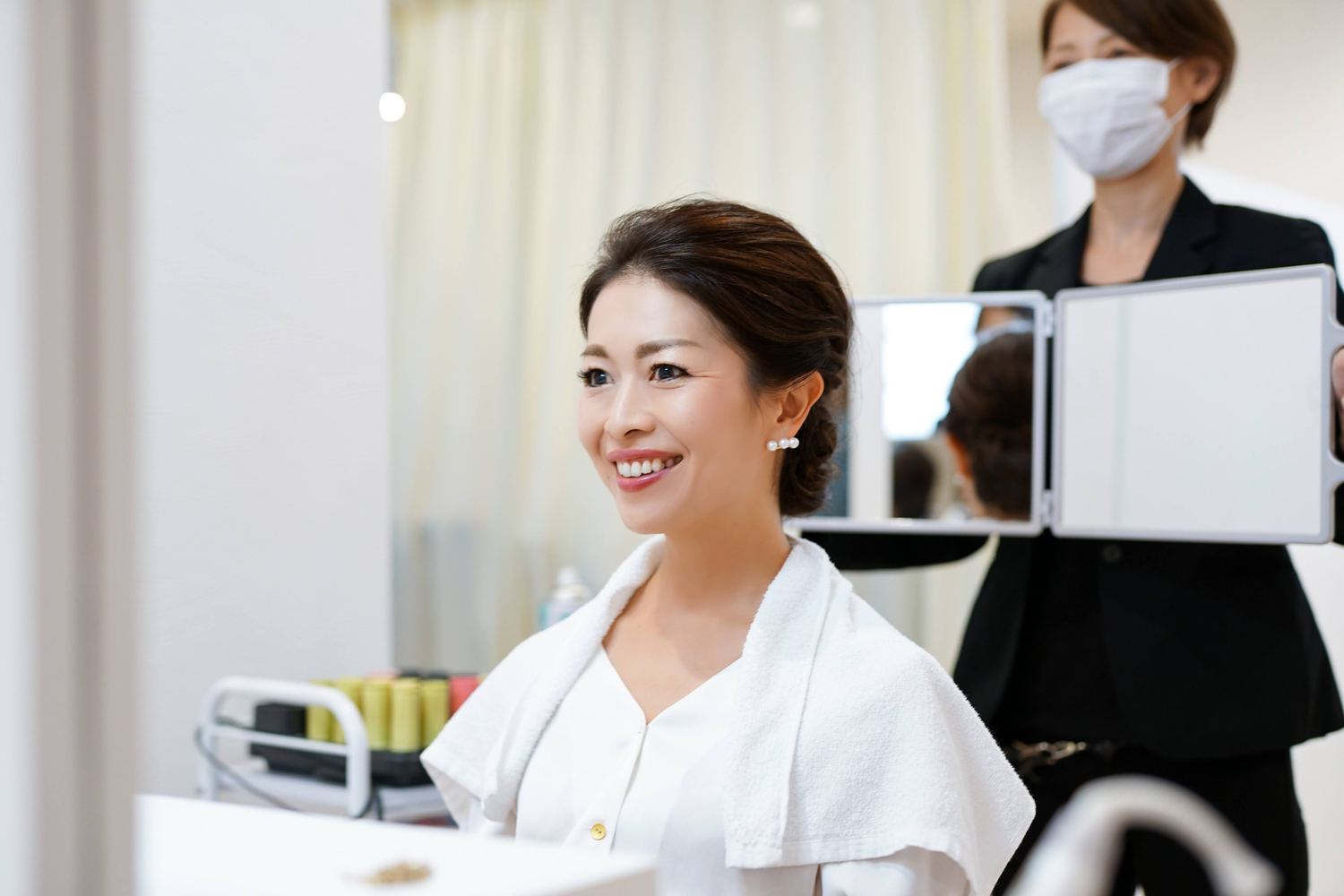 鏡の前で支度をはじめる女性とスタッフ