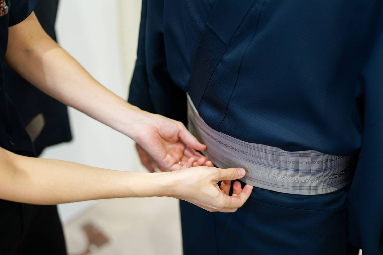 紺の着物に角帯を締める手元