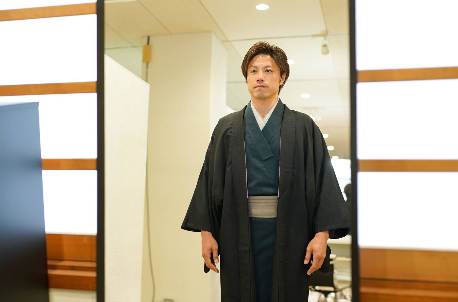 姿見の前に立つ黒い着物姿の男性