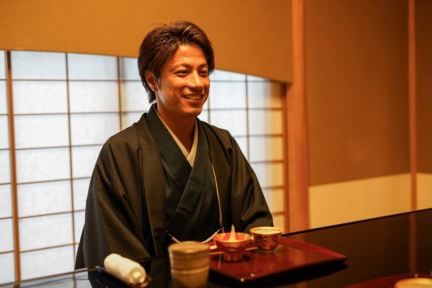 料理屋の席で笑う着物姿の男性