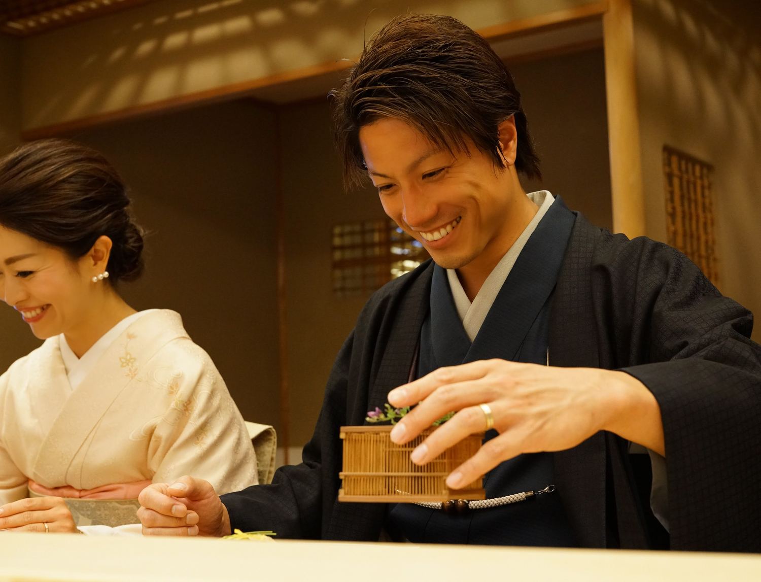 枡を手にする着物姿の男性と見守る女性