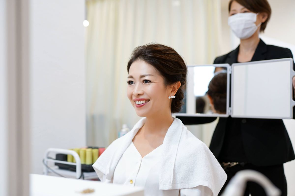 鏡の前でプロのスタイリストにヘアセットを受ける女性