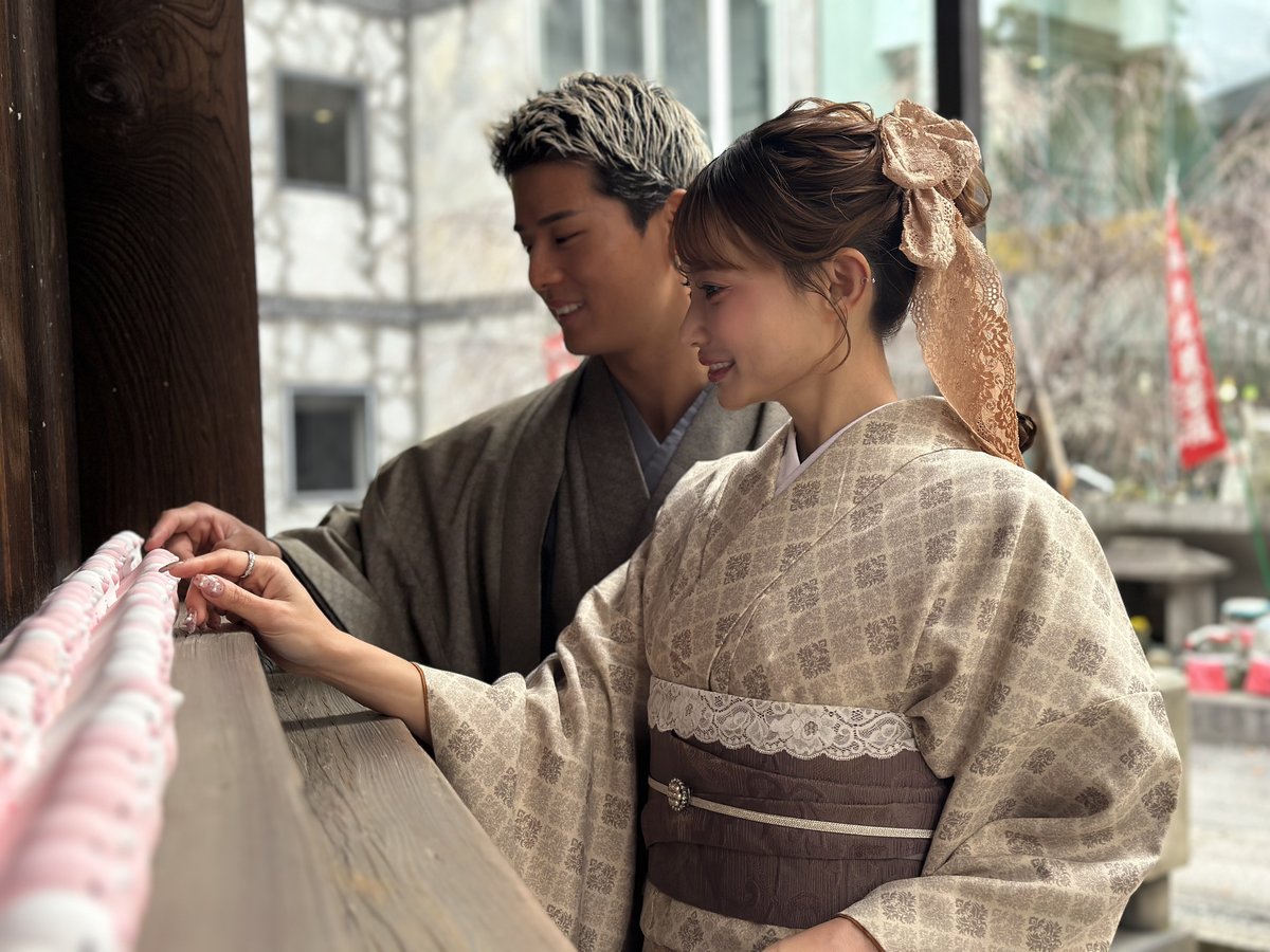 社殿でおみくじを結ぶ着物姿のふたり