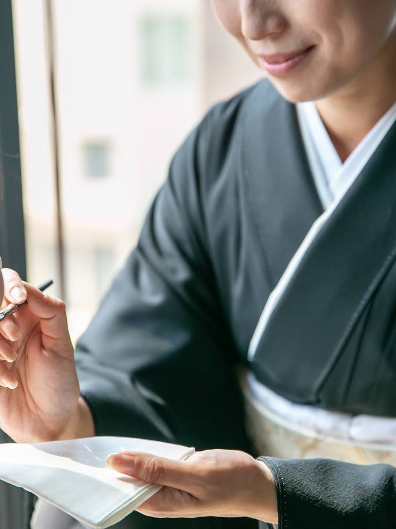 留袖姿で筆をとる手元