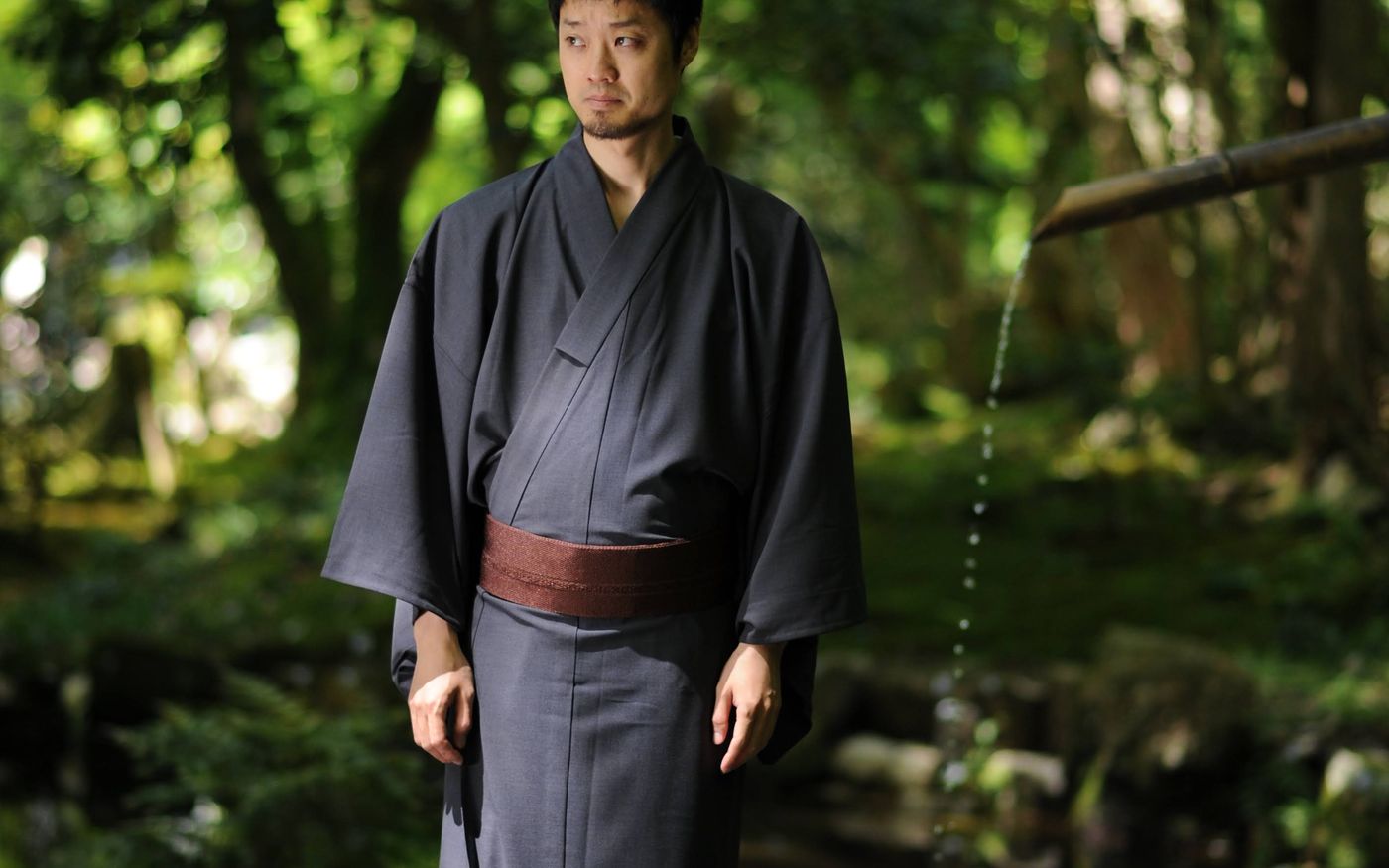 夏の緑の中に佇む着物姿の男性