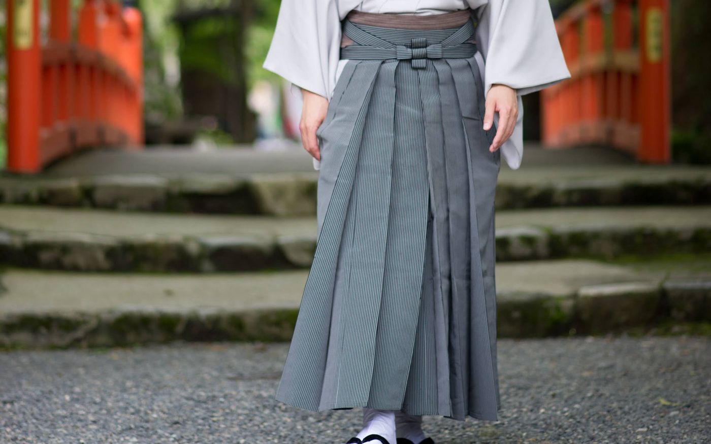 灰色の袴の裾さばき／朱塗りの橋を背に